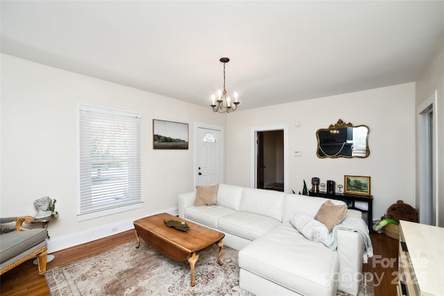 living area with a chandelier, baseboards, and wood finished floors