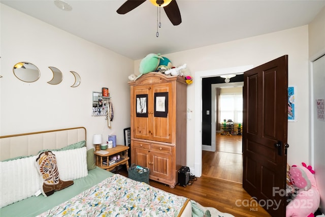 bedroom with ceiling fan, wood finished floors, and baseboards