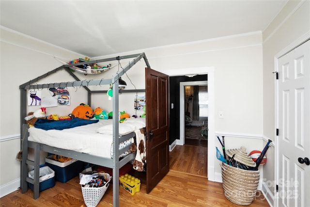 bedroom with light wood-style floors, ornamental molding, and baseboards