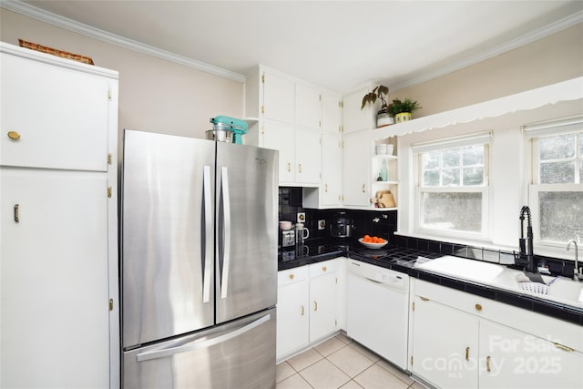 kitchen with tasteful backsplash, ornamental molding, freestanding refrigerator, white dishwasher, and a sink