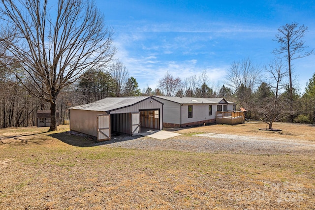 view of front facade with an outbuilding, a front lawn, a garage, an outdoor structure, and a wooden deck