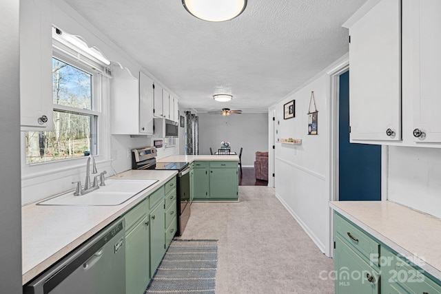 kitchen with green cabinets, stainless steel appliances, a sink, and light countertops