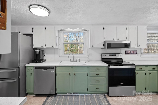 kitchen featuring a sink, white cabinets, light countertops, appliances with stainless steel finishes, and green cabinetry