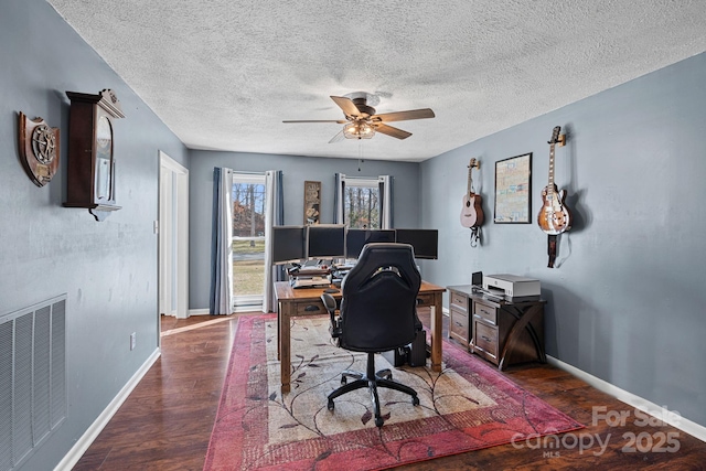 office featuring baseboards, visible vents, ceiling fan, dark wood-style flooring, and a textured ceiling