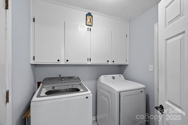 laundry area with washing machine and dryer, cabinet space, and a textured ceiling