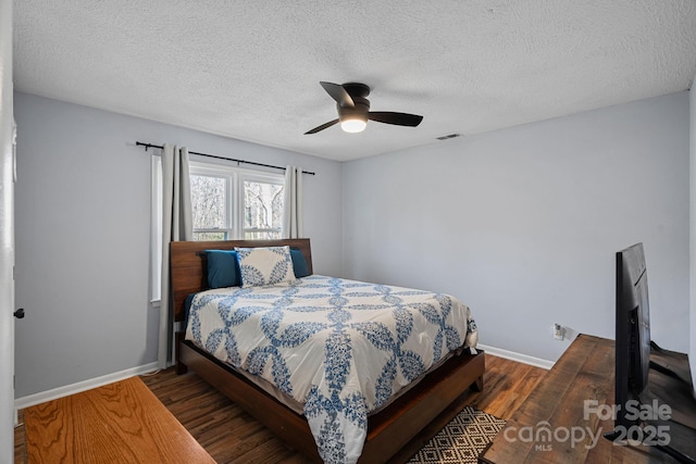 bedroom featuring ceiling fan, wood finished floors, visible vents, and baseboards