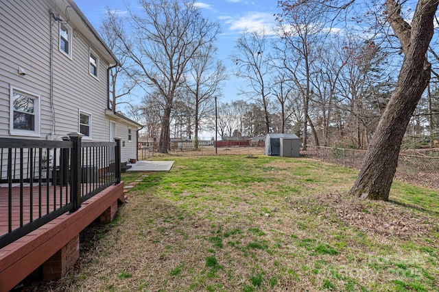 view of yard featuring a fenced backyard, an outdoor structure, a deck, and a shed