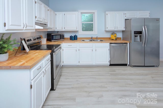 kitchen featuring under cabinet range hood, a sink, white cabinets, appliances with stainless steel finishes, and light wood-type flooring