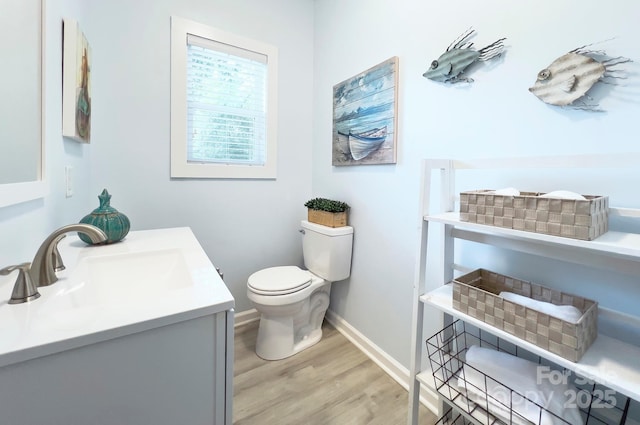 bathroom featuring baseboards, vanity, toilet, and wood finished floors