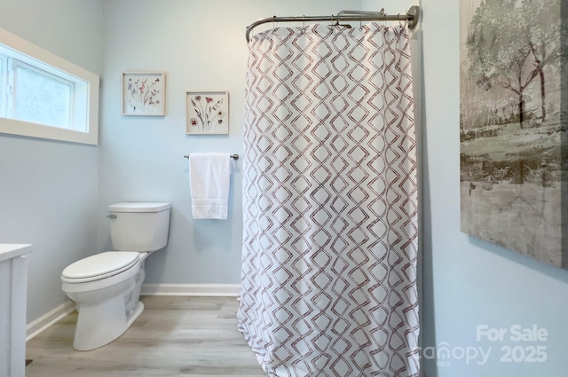 full bathroom with toilet, a shower with curtain, baseboards, and wood finished floors