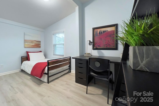 bedroom with lofted ceiling, baseboards, and light wood finished floors