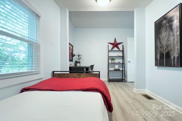 bedroom with visible vents, light wood-style flooring, baseboards, and multiple windows