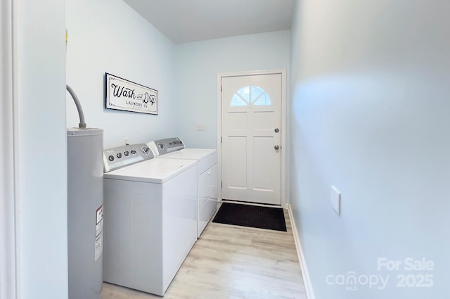 laundry room with light wood-style floors, washing machine and dryer, electric water heater, laundry area, and baseboards