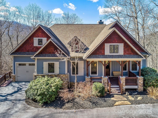 craftsman inspired home featuring a garage, a chimney, aphalt driveway, covered porch, and board and batten siding