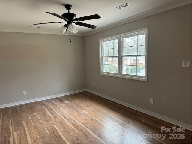 spare room featuring wood finished floors, visible vents, and crown molding