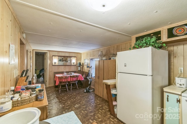 kitchen featuring freestanding refrigerator and wooden walls