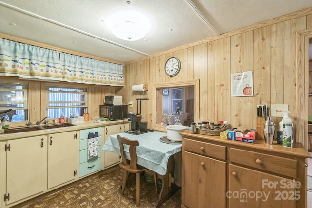 kitchen with light countertops, a sink, and wooden walls