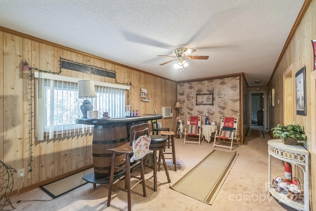 bar featuring crown molding, carpet flooring, wooden walls, a textured ceiling, and a bar