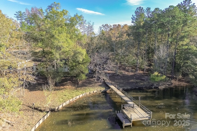 view of dock with a water view and a forest view