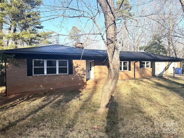 ranch-style home with metal roof, brick siding, a chimney, and a front yard