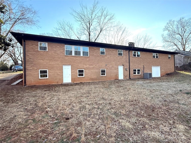 back of house with brick siding and cooling unit