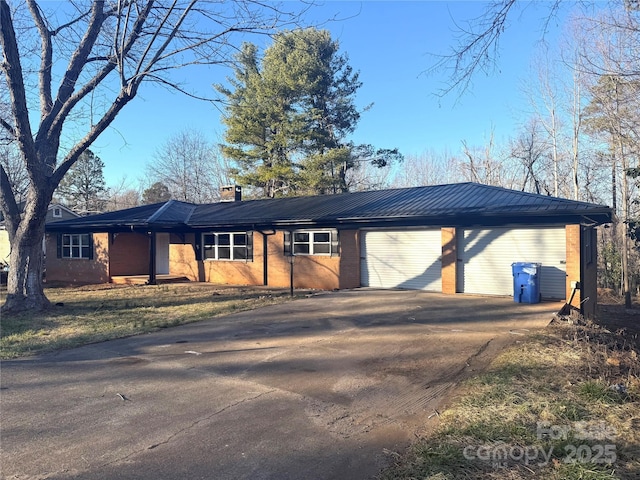 ranch-style home featuring a garage, driveway, and a chimney