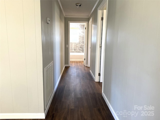 corridor with ornamental molding, dark wood finished floors, visible vents, and baseboards