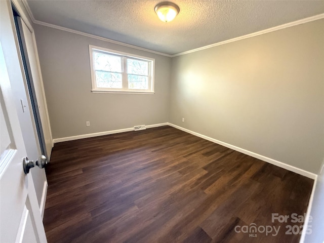 spare room featuring visible vents, baseboards, dark wood-style floors, ornamental molding, and a textured ceiling