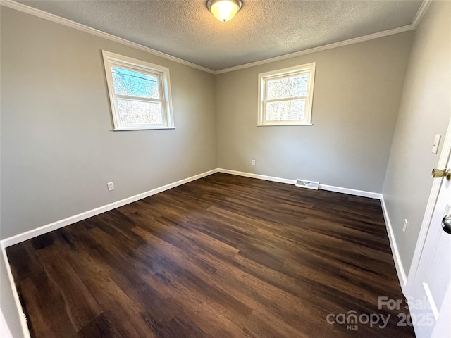 spare room featuring baseboards, dark wood-type flooring, visible vents, and a healthy amount of sunlight