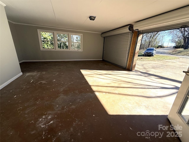 interior space with crown molding, baseboards, and unfinished concrete flooring