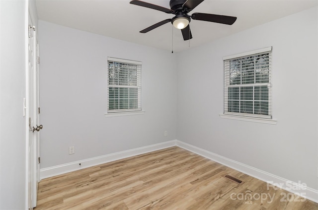 spare room featuring baseboards, ceiling fan, visible vents, and light wood-style floors