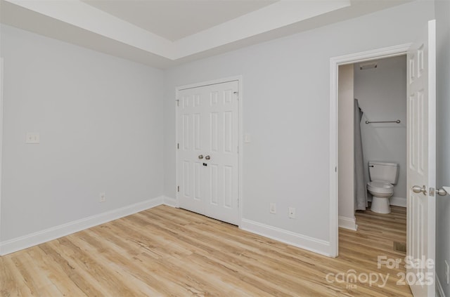 unfurnished bedroom featuring a closet, light wood-style flooring, and baseboards