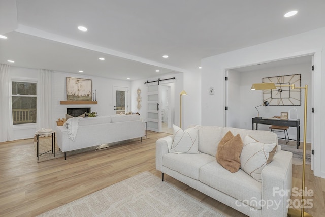 living room featuring light wood finished floors, a barn door, and recessed lighting