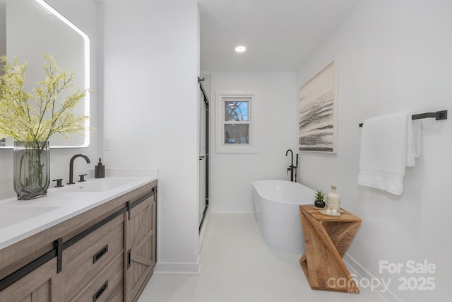 bathroom featuring a sink, baseboards, a soaking tub, a shower stall, and double vanity