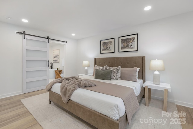 bedroom with recessed lighting, wood finished floors, and a barn door