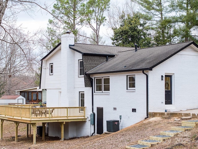 back of property featuring brick siding, roof with shingles, a chimney, crawl space, and a wooden deck