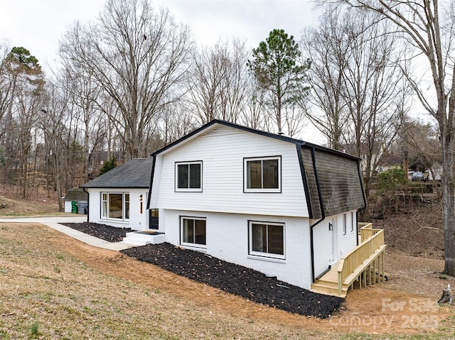 exterior space featuring brick siding and roof with shingles