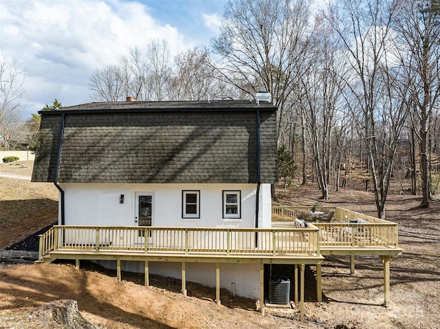 rear view of property with a shingled roof, a deck, and central AC unit