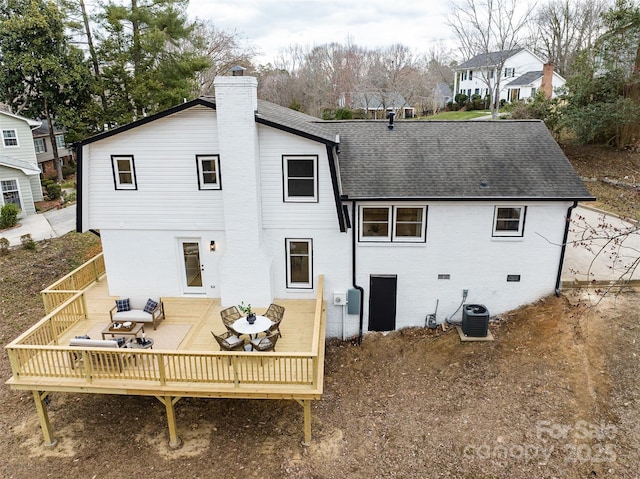 back of house with cooling unit, roof with shingles, crawl space, a wooden deck, and a chimney