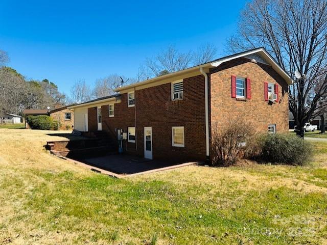 rear view of property with a yard, brick siding, and a patio