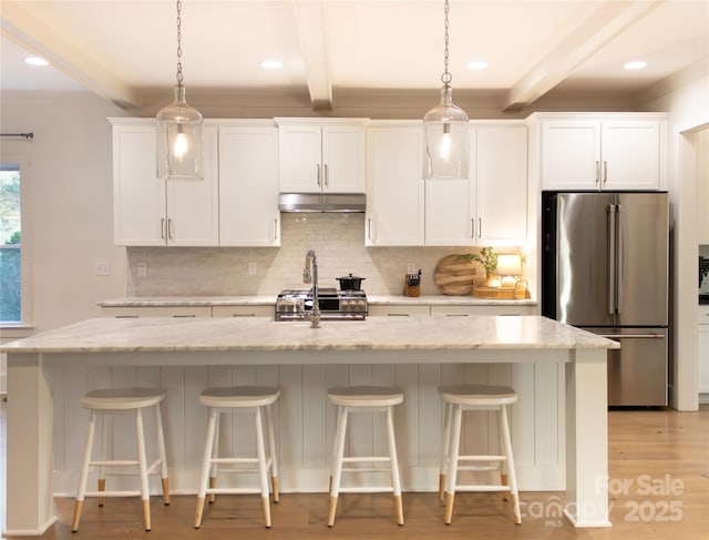 kitchen featuring beam ceiling, stainless steel appliances, backsplash, white cabinetry, and under cabinet range hood