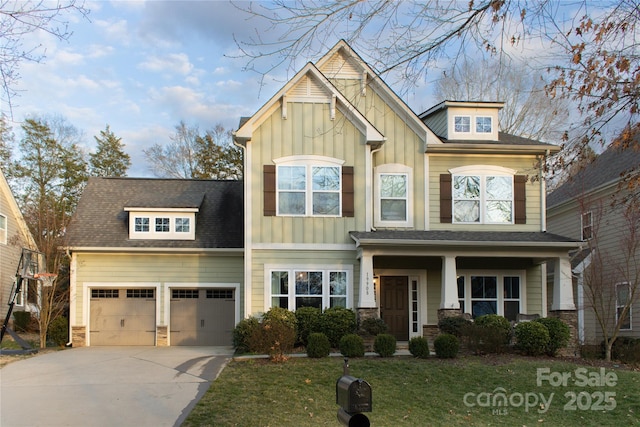 craftsman-style house featuring driveway, stone siding, an attached garage, board and batten siding, and a front yard