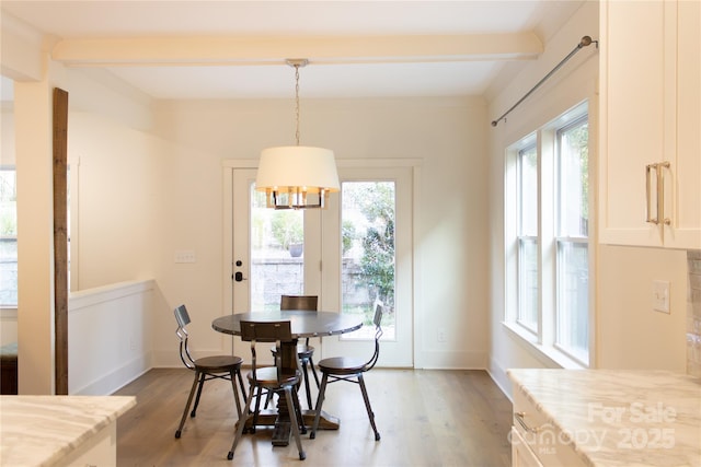 dining space with a wealth of natural light, beam ceiling, and light wood-style flooring