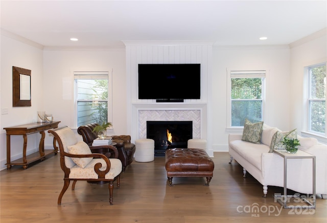 sitting room with crown molding, a fireplace, plenty of natural light, and wood finished floors