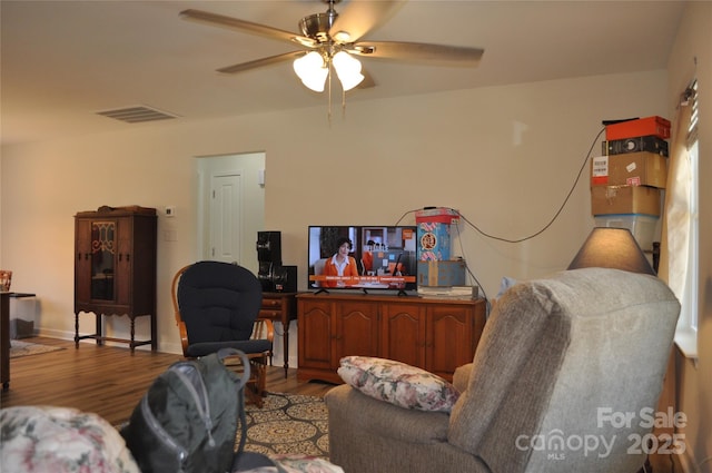 living room featuring a ceiling fan, visible vents, and wood finished floors