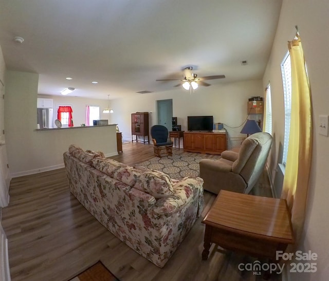 living area featuring baseboards, ceiling fan, wood finished floors, and visible vents