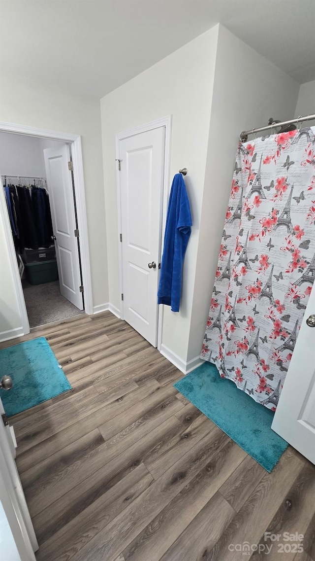 full bathroom featuring baseboards, a shower with curtain, and wood finished floors