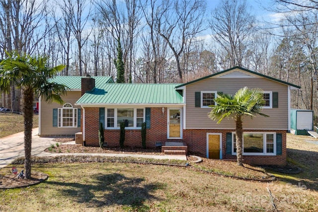 split level home with driveway, a chimney, metal roof, a standing seam roof, and brick siding