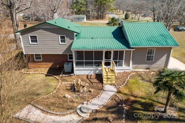 rear view of house with a sunroom, metal roof, crawl space, and a standing seam roof