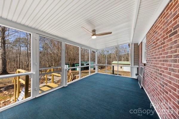 unfurnished sunroom featuring a ceiling fan and a healthy amount of sunlight